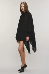 Camisa negra de crepé liviano y translúcido, de calce regular, diseño asimétrico con volados en el lado izquierdo, mangas largas con puños elásticos y volados, cuello redondo y cierre frontal con cartera oculta y botones metálicos.