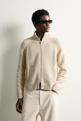 Chaqueta relaxed fit de punto tejido en hilatura con mezcla de algodón, color beige, con cuello subido y manga larga. Cuenta con acabados en rib, efecto lavado y cierre frontal con cremallera.