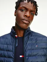 Campera acolchada Tommy Hilfiger color azul marino, con cuello alto y cierre de cremallera. Tiene el logo de la marca bordado en el pecho y detalles distintivos en el cuello. Es plegable y repele el agua.