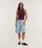 Blusa musculosa básica de color negro, confeccionada en tejido acanalado de algodón con elastano, con cuello redondo y diseño ajustado.