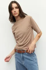 Remera negra de cuello redondo y manga tres cuartos, confeccionada en tela con textura sutil. Presenta fruncidos laterales que aportan caída y movimiento a la prenda.