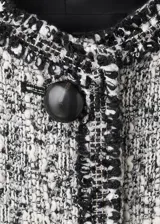 Chaqueta de tweed en tonos gris y blanco, con cuello redondo, manga larga, bolsillos frontales de ribete y cierre delantero con botones.