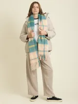 Bufanda de tejido suave con diseño a cuadros en tonos beige y amarillo neón. Presenta flecos en los extremos y una etiqueta de la marca Rusty.