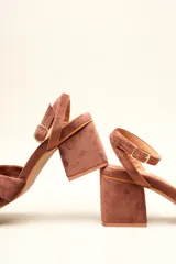 Sandalia de tacón cuadrado medio, confeccionada en terciopelo negro. Presenta un diseño de tiras cruzadas con nudo en la parte delantera y una tira ajustable con hebilla en el tobillo.