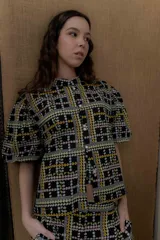 Camisa de popelina de algodón con cuello mao, botones frontales agrupados en pares y mangas cortas abullonadas tipo balloon. Cuenta con un diseño estampado de patrón geométrico y floral sobre fondo negro.