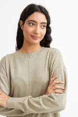 Vestido tipo sweater color blanco, de corte recto y largo hasta la rodilla, con cuello redondo y mangas largas.