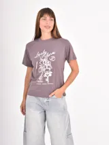 Remera color gris topo con estampa frontal en blanco que incluye gráficos de llaveros y la inscripción "Lucky Charm".