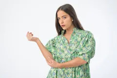 Vestido corto verde con estampado floral, cuello alto, mangas cortas abullonadas y corte holgado.