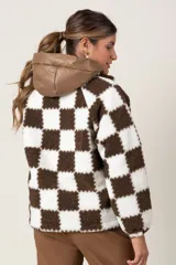 Campera de corderito sintético con diseño de cuadros damero en color crudo y chocolate. Presenta cierre frontal completo, cuello alto y un bolsillo frontal tipo cargo en material sintético con cierre.
