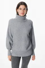 Sweater de tejido de punto con textura acanalada, cuello alto tipo polerón, mangas largas con diseño abuchonado y puños anchos.