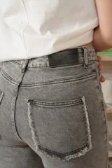 Jean oxford de tiro alto en color azul, con cortes horizontales y diagonales en las rodillas y detalles desflecados en el ruedo.