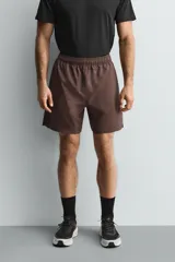 Pantalones deportivos cortos de tejido técnico ligero y elástico, con cintura elástica ajustable, bolsillos frontales y aberturas laterales en el bajo.