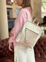 Mochila de cuero en color crudo, con bolsillo frontal con cierre y detalle de textura grabada. Cuenta con tiras ajustables y manija superior.