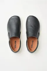 Zapatillas tipo slip-on de gamuza color beige, con diseño barefoot y suela de corcho texturizado. Presenta elásticos laterales negros para un calce fácil.