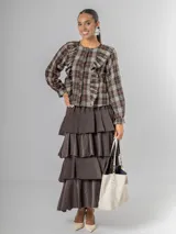 Falda larga de micro corderoy color marrón oscuro, con diseño de volados en capas y elástico en toda la cintura.