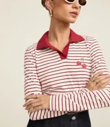 Blusa de algodón a rayas horizontales blancas y rojas, con cuello polo rojo, mangas largas y bordado de cerezas en el pecho.