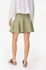 Minifalda color marrón oscuro, confeccionada en lino italiano, con diseño de cintura baja con caderín y bajo acampanado. Cierre invisible en el lateral.