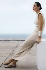 Zapato plano tipo chata, color bronce metalizado, con capellada y forro de cuero vacuno trenzado a mano. Posee un taco bajo de 2,5 cm.