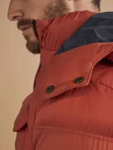 Campera puffer verde militar con capucha, cierre frontal, bolsillos laterales con cierre y un bolsillo de solapa en el pecho.