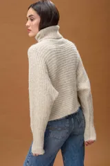 Sweater de punto con cuello alto, manga larga y diseño holgado. Presenta una textura suave con un sutil acabado brillante.