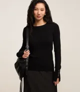 Suéter ajustado de punto color crema, con cuello redondo y mangas largas con botones metálicos en los puños. Confeccionado con viscosa sostenible.