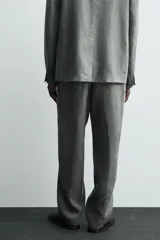 Pantalón de corte straight relaxed fit confeccionado en tejido de lino. Presenta cintura con pliegues frontales, cierre frontal con cremallera y botón, bolsillos laterales y bolsillos traseros con solapa.