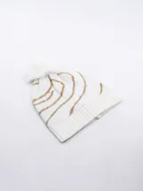 Gorro de lana tejido, color blanco, con diseño de rayas onduladas en hilo dorado y pompón de pelo sintético blanco en la parte superior.