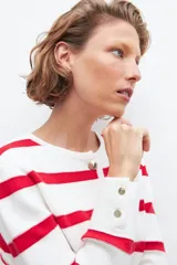 Chaqueta tejida con rayas horizontales rojas y blancas, cuello redondo y botones dorados.