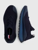 Zapatillas de running Tommy Hilfiger color azul marino, confeccionadas en tejido de punto elástico de poliéster reciclado. Cuentan con plantilla de acupresión, suela dentada de goma y caucho, trabilla distintiva y monograma TH grabado en la entresuela.