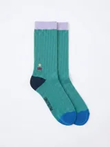 Medias de caña media con diseño acanalado en color verde, con puño en color lila, talón en azul marino y puntera en azul brillante. Presentan un pequeño bordado de una estrella y líneas horizontales, además del logo de la marca estampado en la parte inferior.