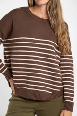 Sweater de punto con diseño a rayas horizontales negras sobre base color crema, cuello redondo, mangas largas y puños acanalados.