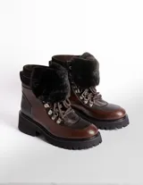 Borcegos de cuero vacuno en tonos marrón, con diseño de caña media y cuello con forro de piel sintética negra. Presentan cordones marrones, ganchos metálicos para ajuste y suela de goma tipo track con plataforma.