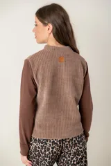 Polera de manga larga con diseño combinado, presentando un cuerpo de textura acanalada en tono marrón claro y mangas lisas en un tono marrón más oscuro. Posee cuello alto y corte recto.