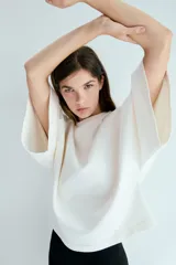 Remera oversized en tejido de felpa liviano color blanco, con mangas anchas al codo y cuello redondo ribeteado.