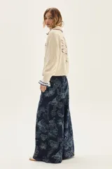 Cardigan de punto color crudo con textura, cuello camisero con borde en contraste, mangas largas con puños acampanados y detalle de bordado floral en la espalda.