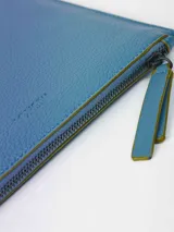 Sobre de símil cuero con efecto floater, color celeste, de diseño pequeño y liviano. Cuenta con forro de algodón, pequeño bolsillo interior y sistema de apertura con cierre metálico.
