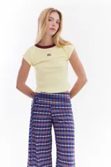 Top de canalé amarillo con cuello redondo y ribetes en color bordo, mangas cortas y detalle de logo bordado en el pecho.