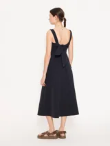 Vestido midi negro de poplin con lycra, silueta línea A, bolsillos plaqué en los laterales y tajo en el centro delantero. Se ajusta en la espalda mediante un lazo.