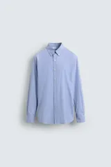 Camisa de corte regular fit confeccionada en tejido de algodón con estampado de rayas verticales. Presenta cuello abotonado, manga larga con puños abotonados y cierre frontal de botones.