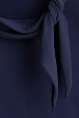 Buzo en punto fino de color azul marino, de corte entallado, con mangas largas, cuello pañuelo con detalle de nudo lateral y remate acanalado en los puños y el bajo.