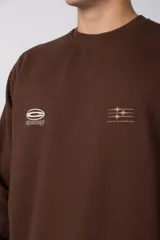 Buzo de cuello redondo en color arena, con diseño de calce regular y estampado gráfico minimalista en el pecho. Presenta puños y ruedo acanalados, con un pequeño detalle de etiqueta en el puño izquierdo.