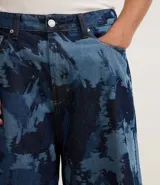 Bermuda de hombre en modelo baggy relaxed, confeccionada en jeans de algodón con estampado manchado en tonos azules. Presenta cintura con trabilla, cierre tradicional y bolsillos.