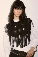 Top de cuero vacuno negro con diseño estilo navajo, caracterizado por flecos largos en todo el contorno y apliques metálicos circulares con detalles de cuentas de madera.