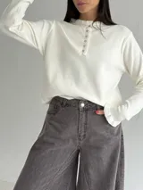 Sweater de punto color marrón chocolate, con cuello redondo y cierre frontal parcial con botones. Presenta mangas largas con puños acampanados y detalle de volados.