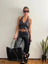 Pantalón negro de cuero sintético con flecos en los laterales.