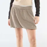 Falda corta estilo globo con estampado de cuadros pequeños en tonos beige y marrón. Presenta una cintura elástica cómoda y un corte voluminoso característico del diseño tipo globo.
