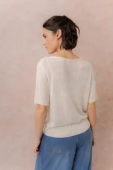 Cardigan tejido de manga corta color beige, con escote redondo amplio y abotonadura frontal con botones al tono. Presenta un calce relajado y terminaciones en rib en la cartera y el ruedo.