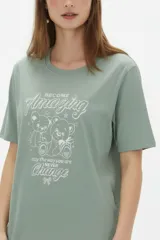 Remera de algodón blanca, de corte holgado, con cuello redondo y diseño estampado en el centro que incluye un gato comiendo de un plato y la inscripción 'Wild Cats'.