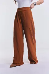 Pantalón camel de corte palazzo, con cintura alta con detalle de frunces y textura arrugada.