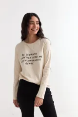 Remera de manga larga color beige con cuello redondo a la base. Presenta un estampado frontal con un dibujo de labios en color fucsia y la palabra 'BESITO' en color negro.